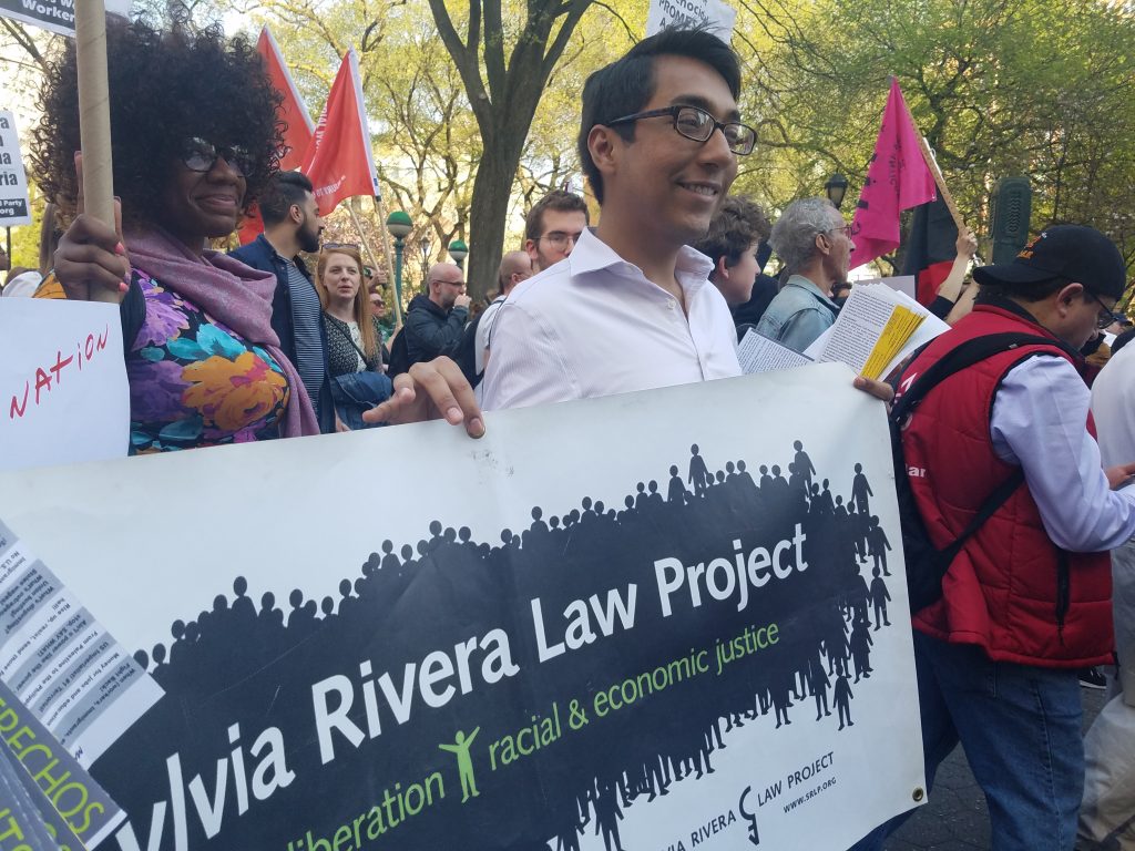 Carlos, SRLP's Direct Services Team intern, marching with SRLP. Carlos is holding up a banner with SRLP's name.